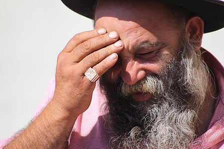 man wearing pink collared shirt and ring touching forehead thumbnail
