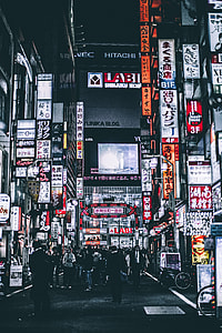 grayscale photo of group of people across the buildings thumbnail