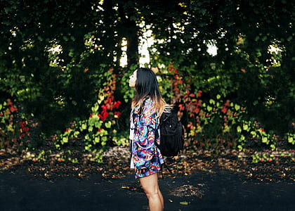 woman wearing backpack standing near green trees thumbnail