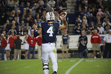 football player holding football on football field thumbnail