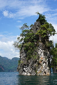 white and black rock formation with green leafed trees on body of water at daytime thumbnail