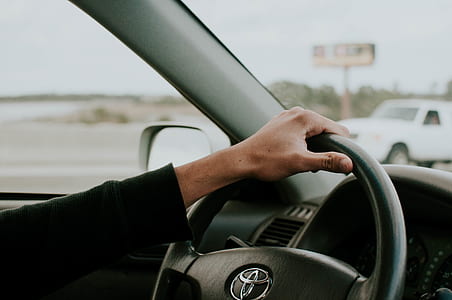 person holding black Toyota steering wheel inside car thumbnail