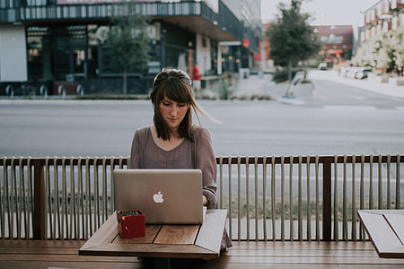 woman in grey 3/4 sleeve top facing MacBook on brown table thumbnail