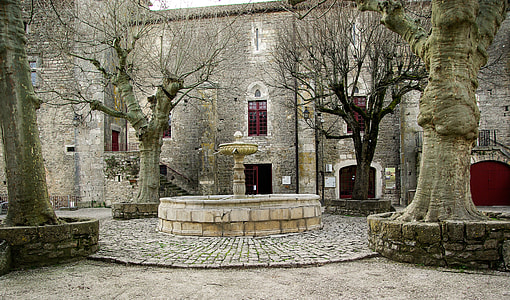 white concrete fountain in front of gray concrete mansion thumbnail