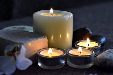 four lighted candles in candle holders thumbnail