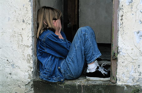 girl in blue jeans and denim jacket with black sneakers covering her face thumbnail