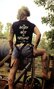 woman wearing black sleeveless shirt and blue-washed denim short shorts thumbnail