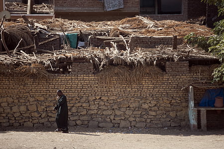 man walking beside brick wall thumbnail