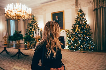 woman standing inside room with christmas trees near walls thumbnail