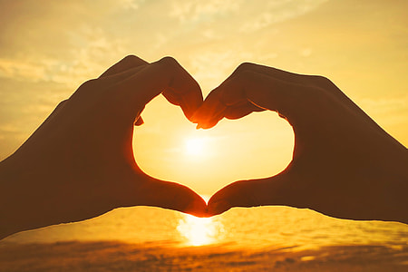 human hand formed heart with gold hour long exposure photo thumbnail