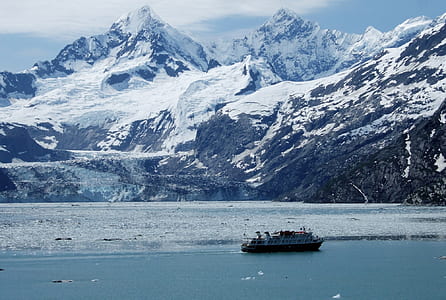 white and black boat near mountain under blue sky thumbnail
