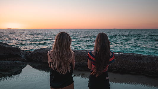 two women standing in front of body of water thumbnail