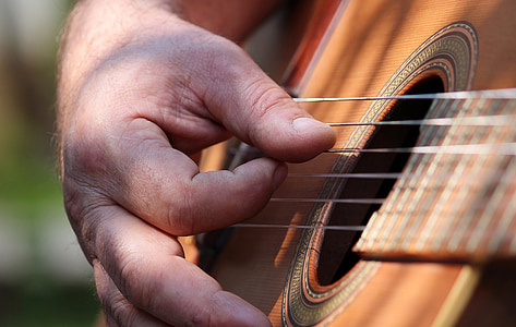 macro photography of man using guitar thumbnail