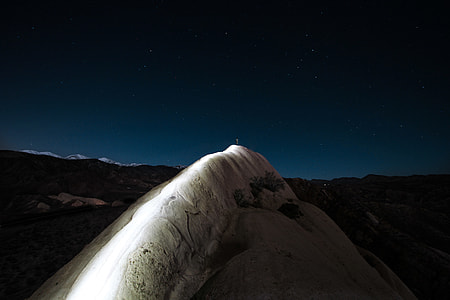person standing on white cliff during nighttime thumbnail