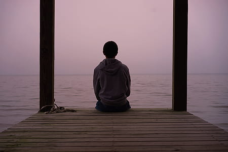 person sitting on wooden pier during daytime thumbnail