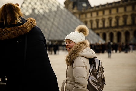 girl wearing brown bubble jacket standing near Louvre museum at Paris during daytime thumbnail
