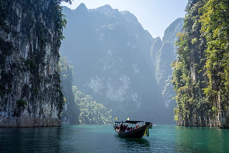 boat on body of water between rock formations thumbnail