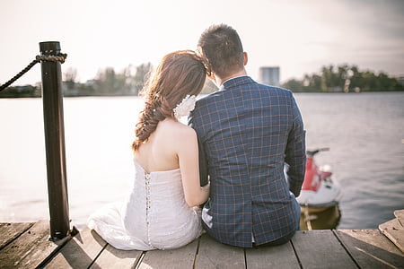 couple siting on sea dock in front of a personal watercraft thumbnail