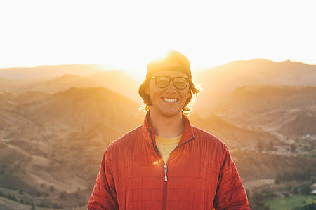 Man in glasses with smile standing in the sunlit mountains thumbnail