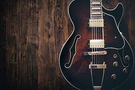 black and brown electric guitar on brown wooden surface thumbnail
