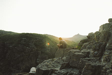 person sitting on rock at edge of mountain thumbnail
