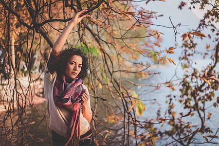 Woman Standing Beside Bare Tree Near Body Of Water thumbnail