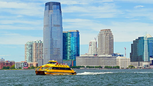 A yellow New York Water Taxi cruises pass Jersry City waterfront on the Hudson River out toward New York Harbor for a siteseeing cruise. thumbnail