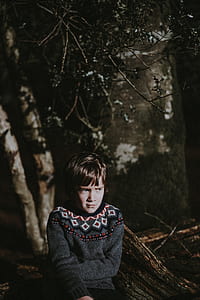 boy sitting on tree log under leafs thumbnail