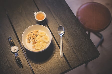 white ceramic bowl beisde spoon and round watch with black leather strap on brown wooden table thumbnail