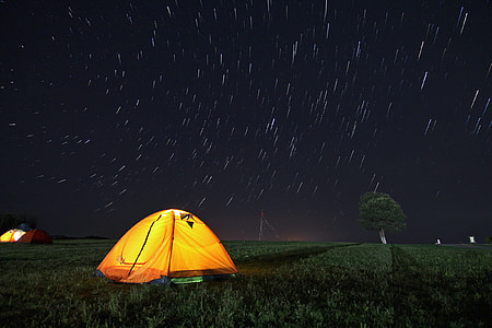 turned-on light inside camping tent under time-lapse photography of stars thumbnail