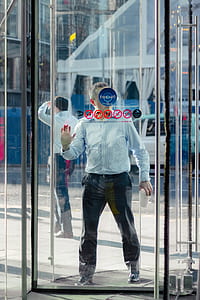 man entering store using glass door thumbnail