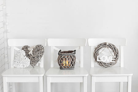 gray wicker wreath and candle holder on top of three white wooden chairs thumbnail