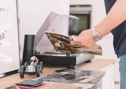 man holding record sleeve while standing in front of black turntable on top of brown sideboard inside well lighted room thumbnail