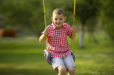 smiling boy sitting on gray swing chair thumbnail