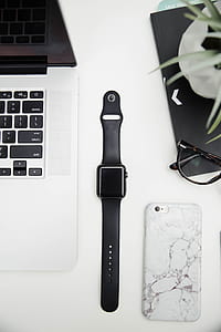 space gray Apple Watch with black Sports Band between laptop and iPhone thumbnail