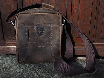 brown leather crossbody bag learning on brown wooden wall thumbnail