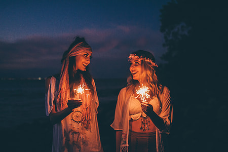 Two women smile at sunset holding sparklers thumbnail