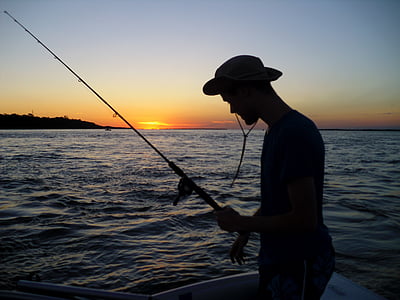 silhouette of man holding fishing rod at sea thumbnail
