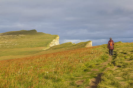 person standing on green mountain during daytime thumbnail