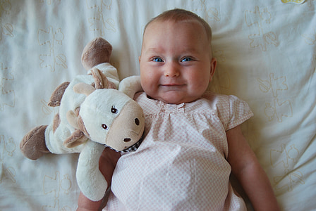 high angle photography of baby in white top laying on bed beside white cow plush toy thumbnail