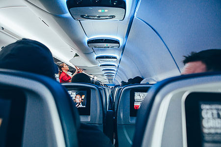 woman in red top standing while looking at luggage thumbnail