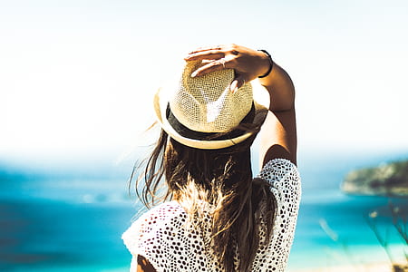women standing holding hat facing sea thumbnail