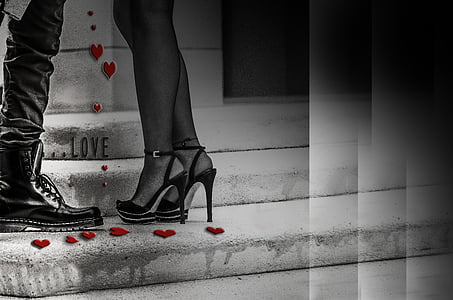 grayscale photo of woman wearing heeled sandals beside man wearing boots thumbnail