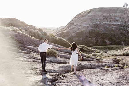 man and woman holding hands while walking on gray mountain during daytime thumbnail