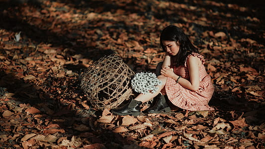 Woman Wearing Red Dress Sitting on Brown Ground With Woven Brown Basket thumbnail