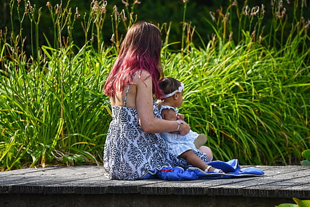 woman holding baby near green grass thumbnail