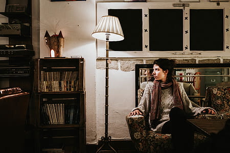Woman Sitting on Sofa Chair Beside Floor Lamp Leaning on Side thumbnail