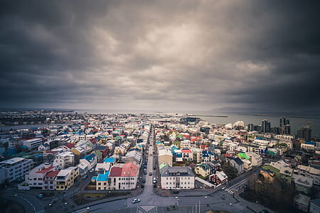aerial view of town under cloudy skies during daytime thumbnail