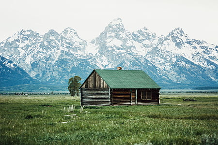 brown and green wooden house near mountain thumbnail