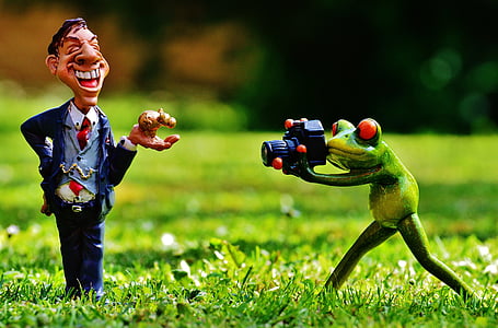 frog holding camera taking picture of a man holding pet figurine thumbnail